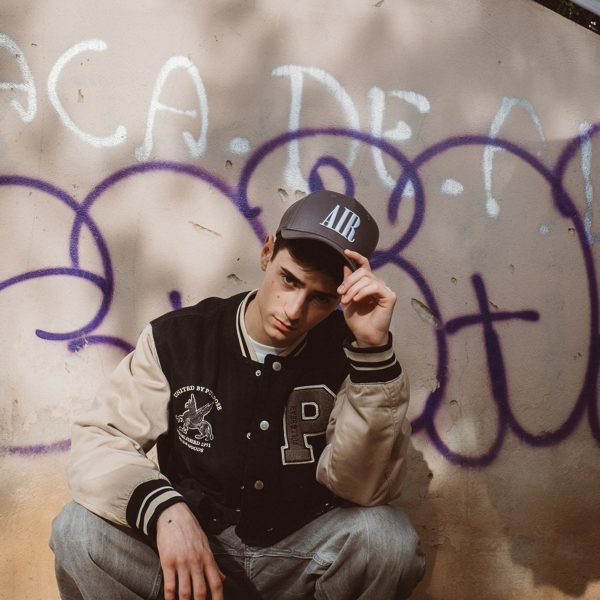 Ung mand i sort baseball cap med AIR logo foran graffiti væg