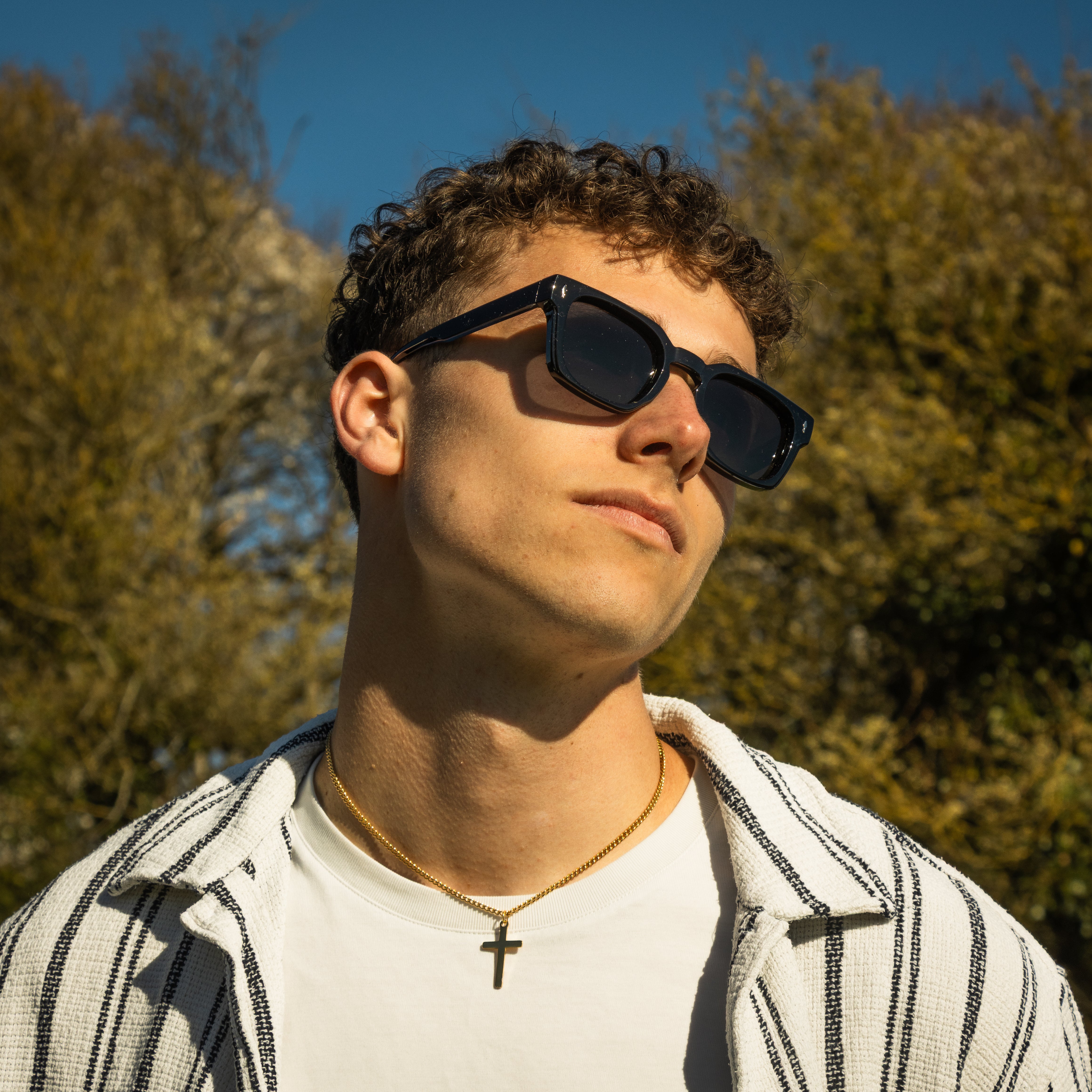 Sorte solbriller på mandlig model, der kigger mod solen.