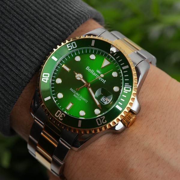 Bellargent dykkerur med grøn urskive og guldlænke på håndled