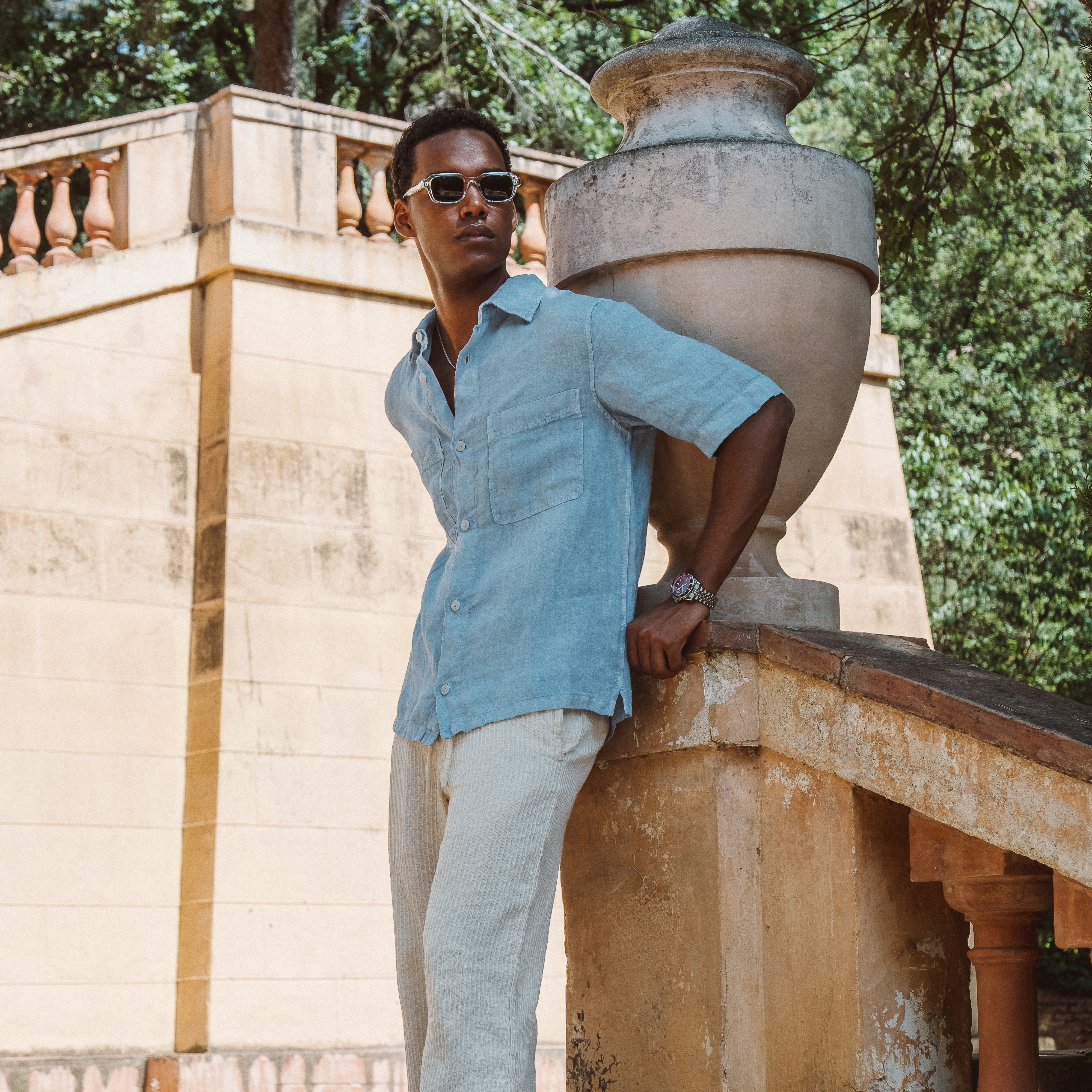 Mand iført blå kortærmet skjorte og solbriller ved stenskulptur