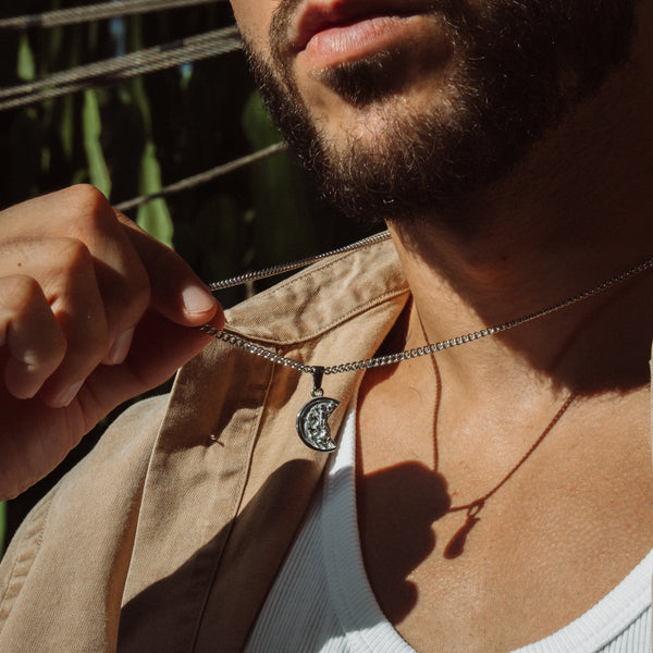 Mand med skæg bærer sølvfarvet halskæde med månevedhæng
