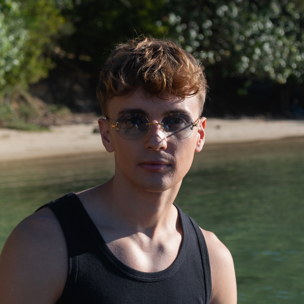 Ung mand med blå solbriller på stranden i sort tanktop