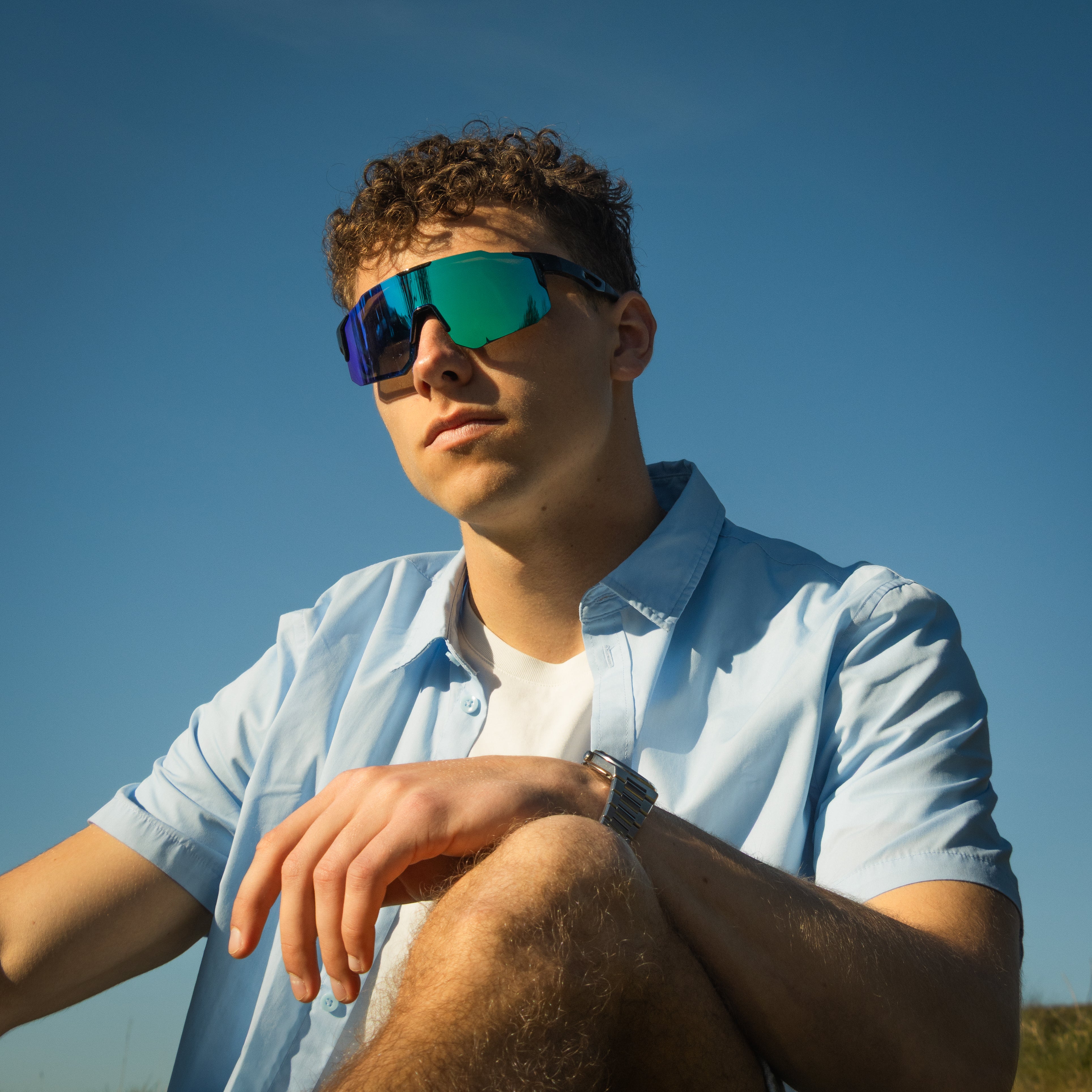 Mand bærer Noire Murky sportsbriller i petrol med blågrønne spejlglas udendørs