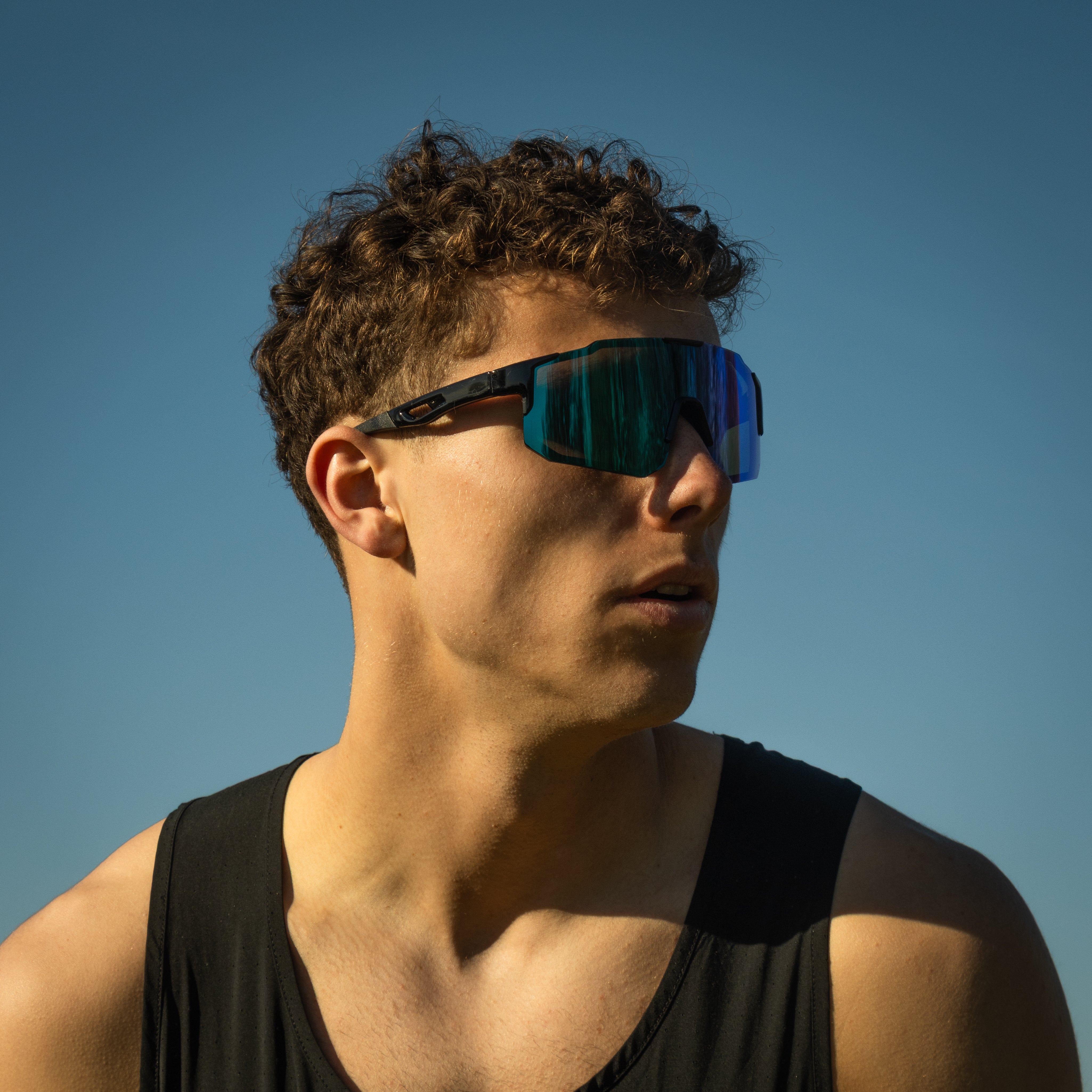Sportsbriller Noire Murky i petrol med blå spejlglas båret af mand udendørs