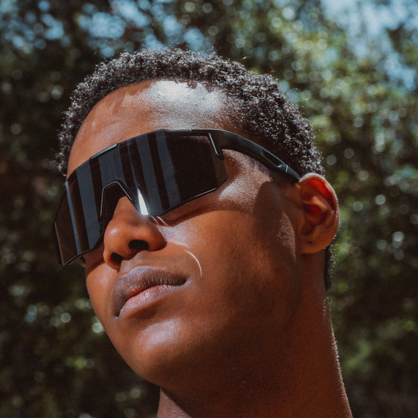 Sort sportsbrille med store mørke linser på model udendørs
