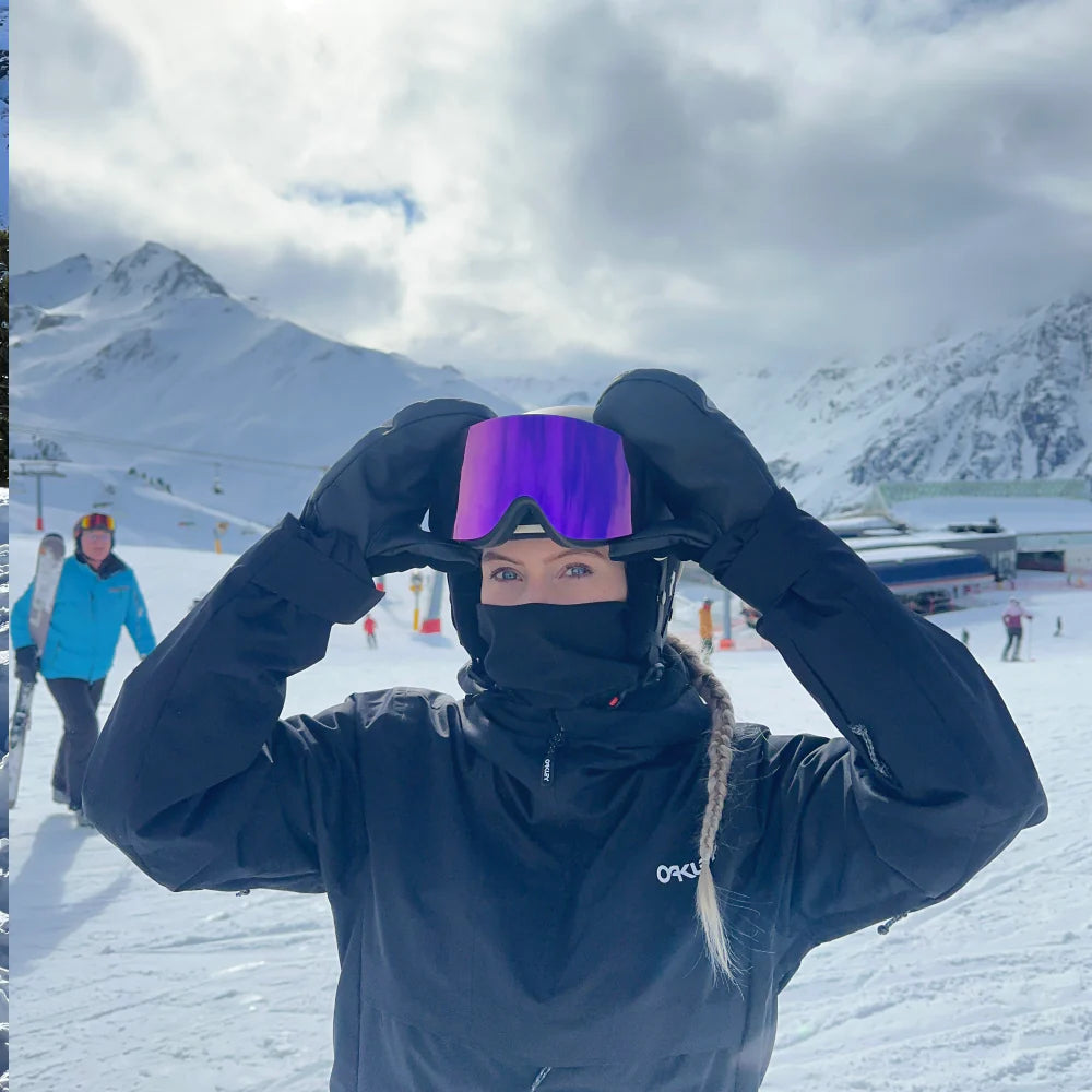 Kvinde justerer Glaciér skibriller med lilla linser på snedækket piste