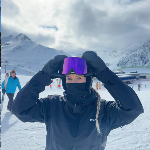 Kvinde justerer Glaciér skibriller med lilla linser på snedækket piste