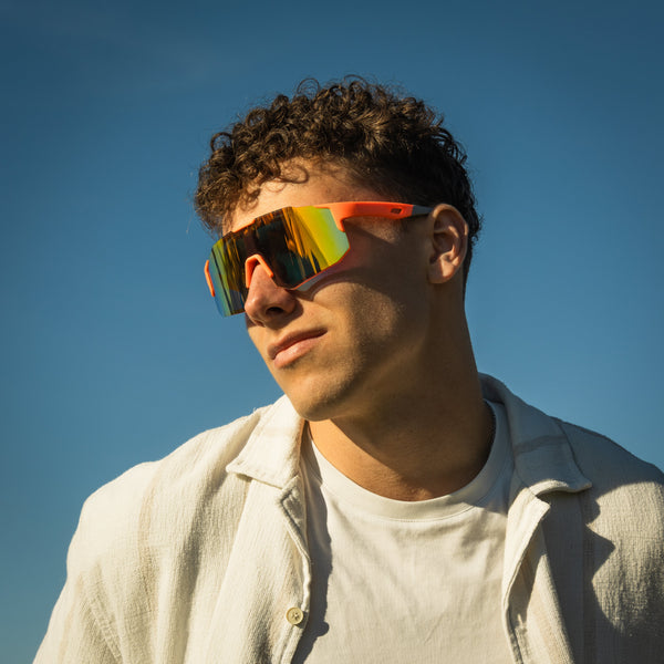 Sportsbriller Noire Orange med orange stel og spejlende glas på model udendørs