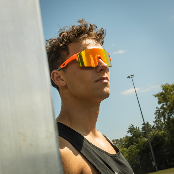 Sportsbriller med orange stel og gule spejlglas båret af mandlig model udendørs