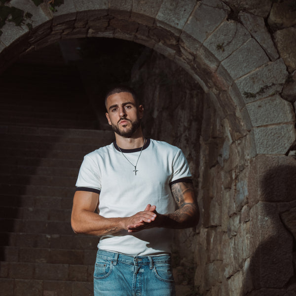 Mand med sølvfarvet kors halskæde i hvid t-shirt