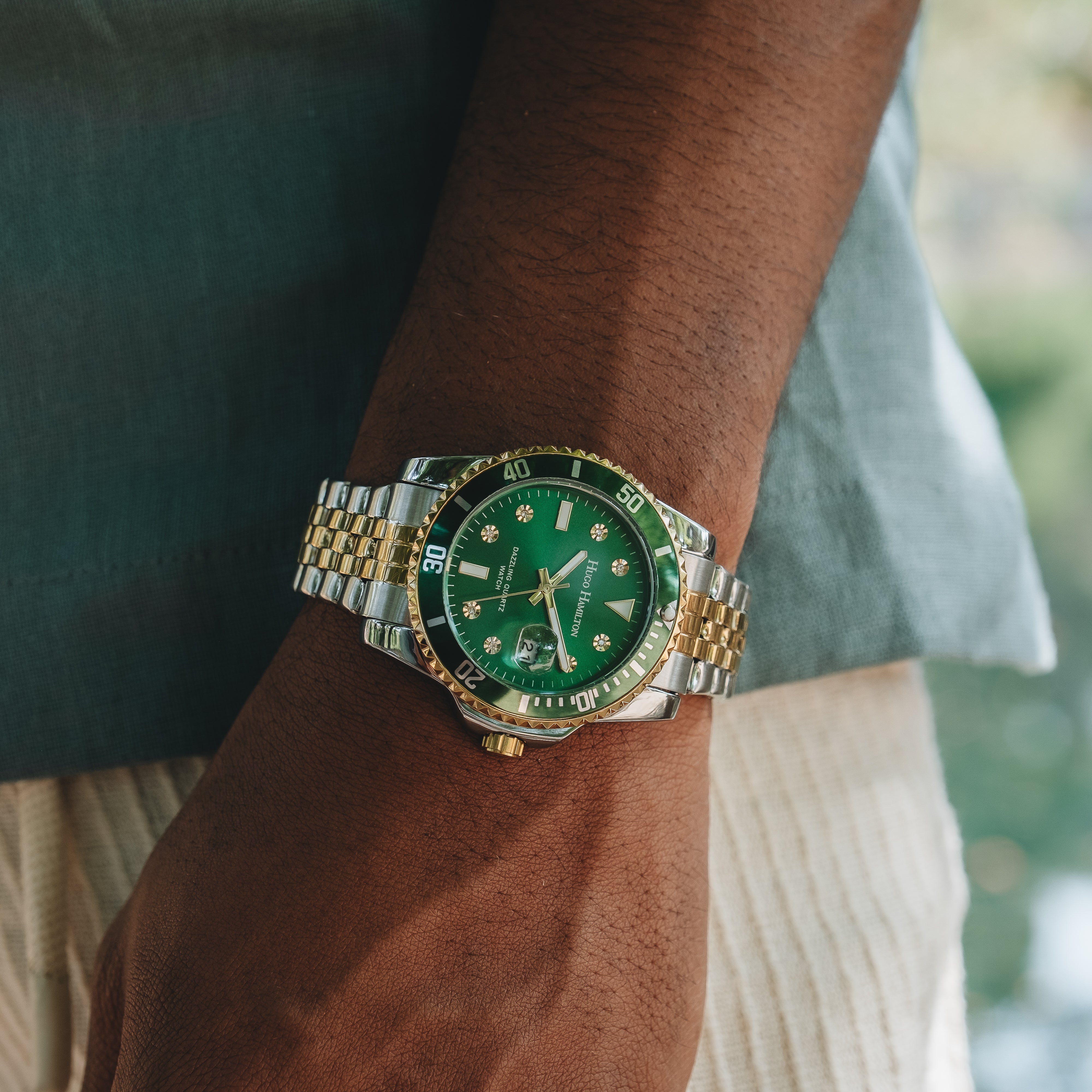 Armbåndsur med grøn urskive og tofarvet stållænke på håndled