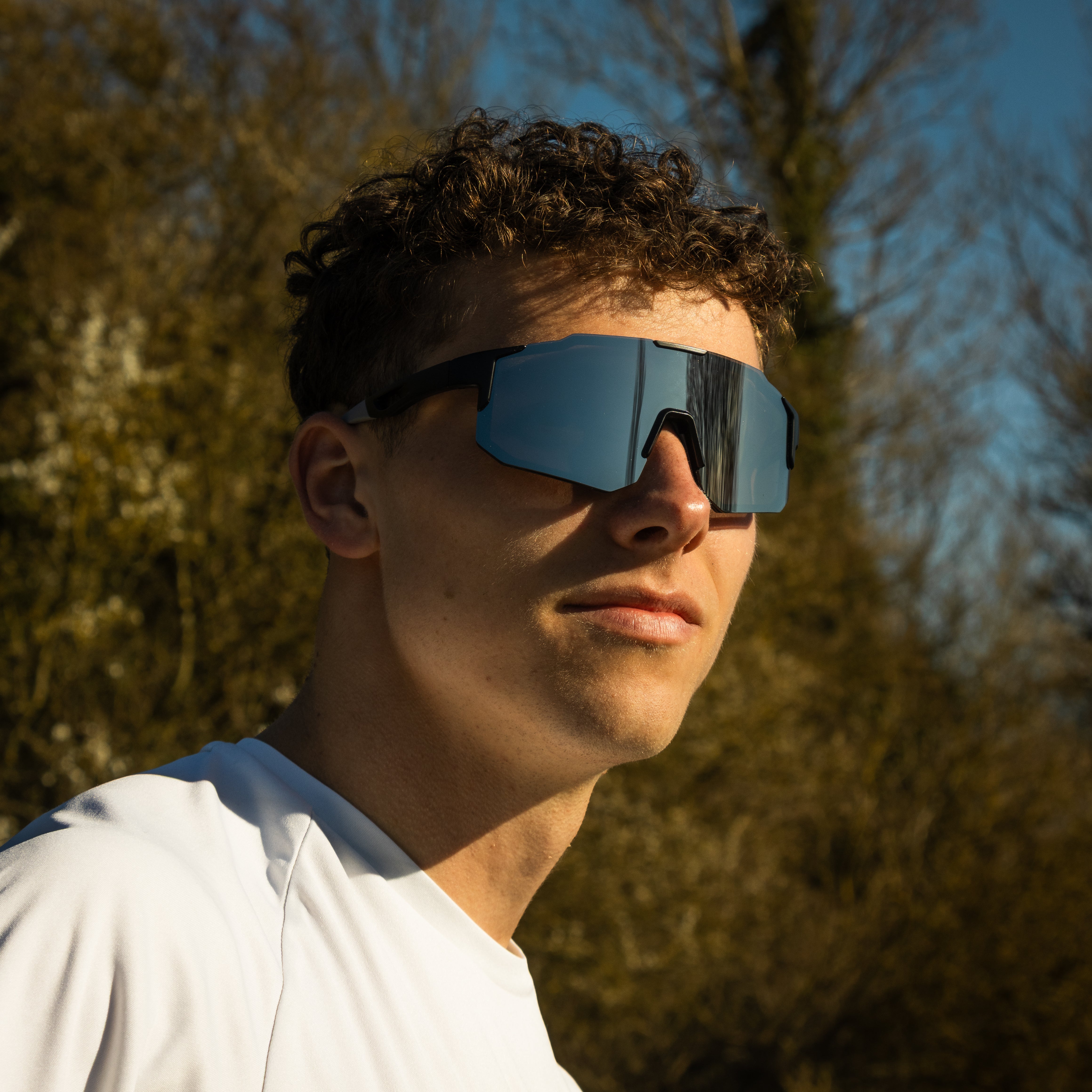 Mand med Noire Steely sportsbriller i grå med blåt spejlglas udendørs