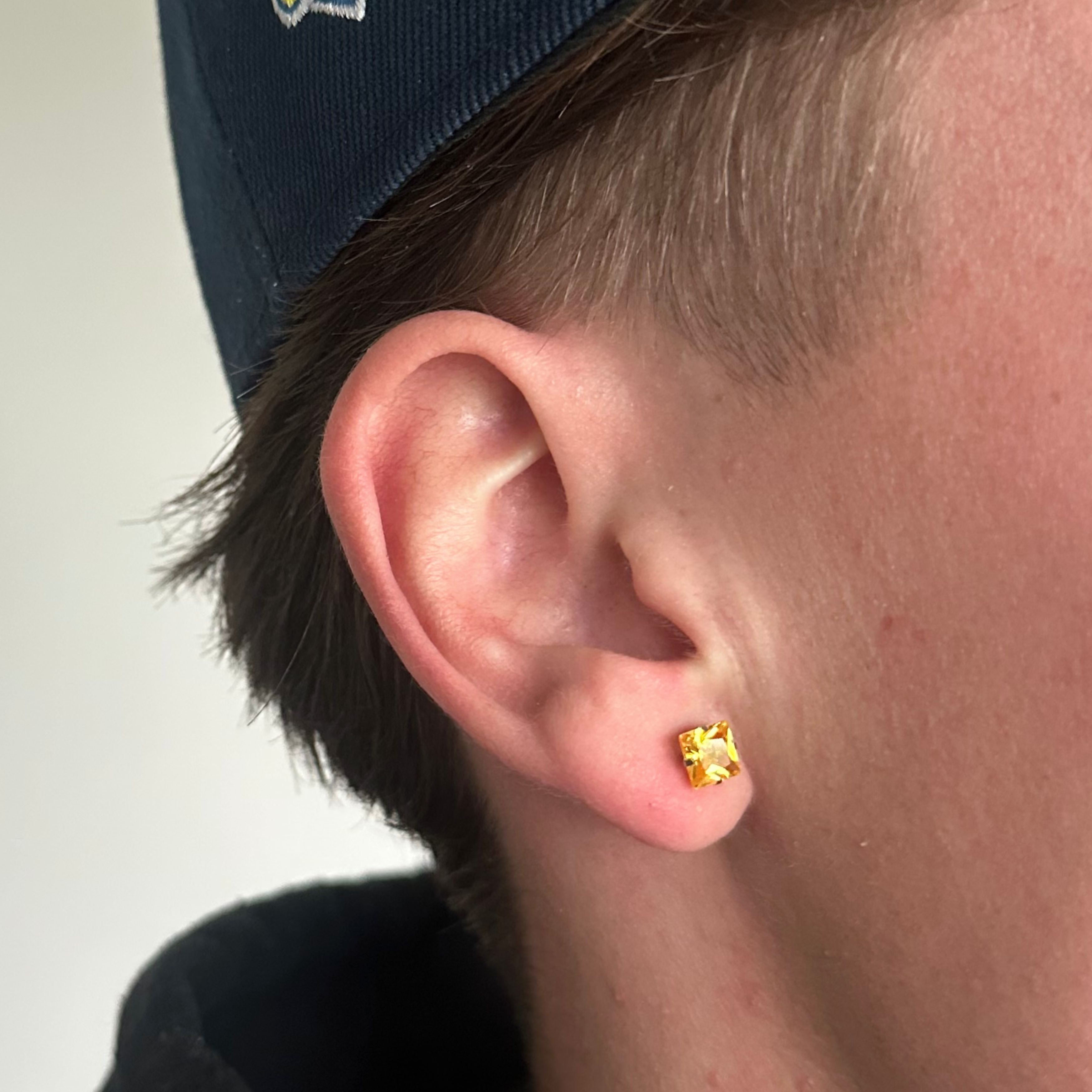 Gul ørering i 6mm på øre med kasket