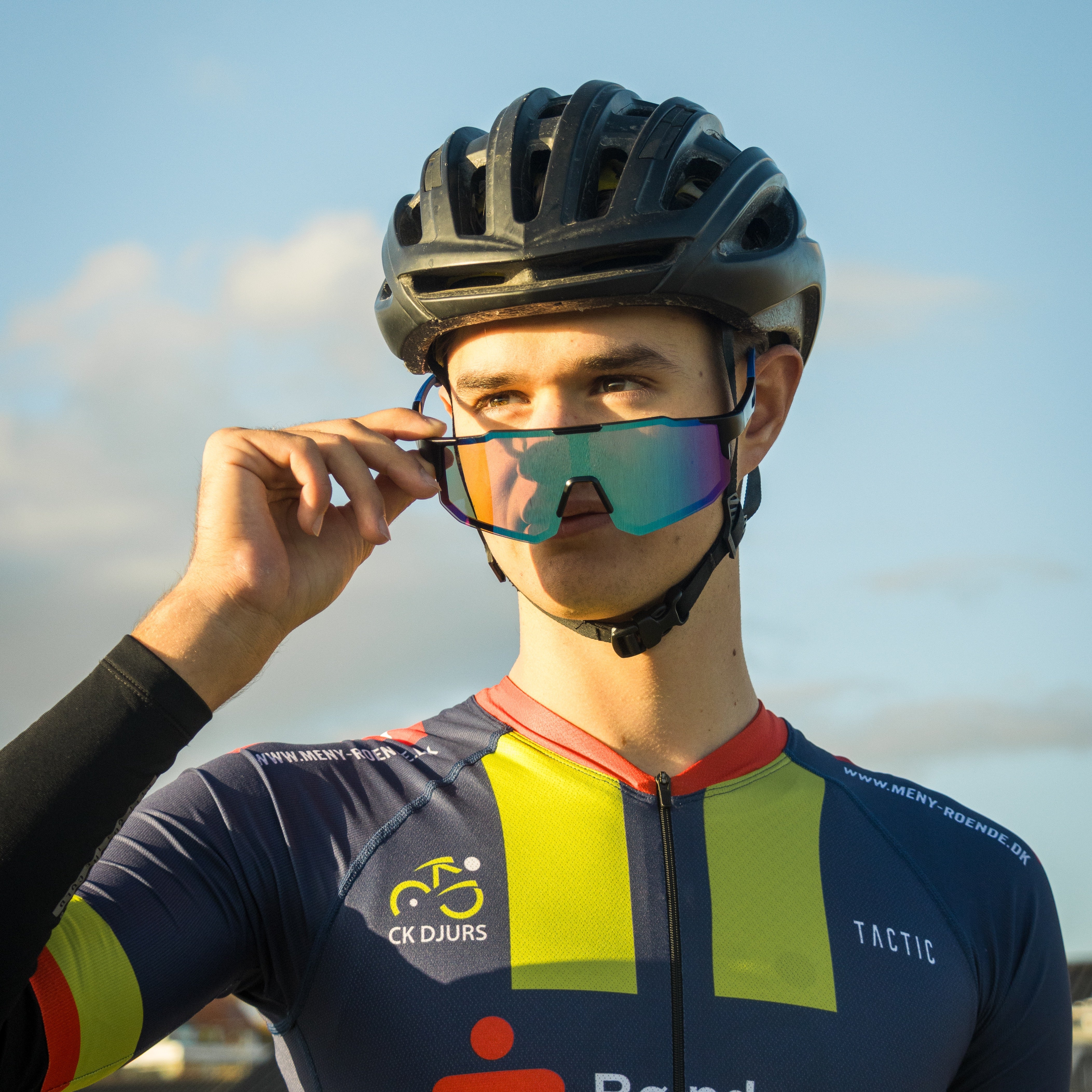 Cyklist med Noire Purplish sportsbriller i blå med farvet spejlglas og cykelhjelm