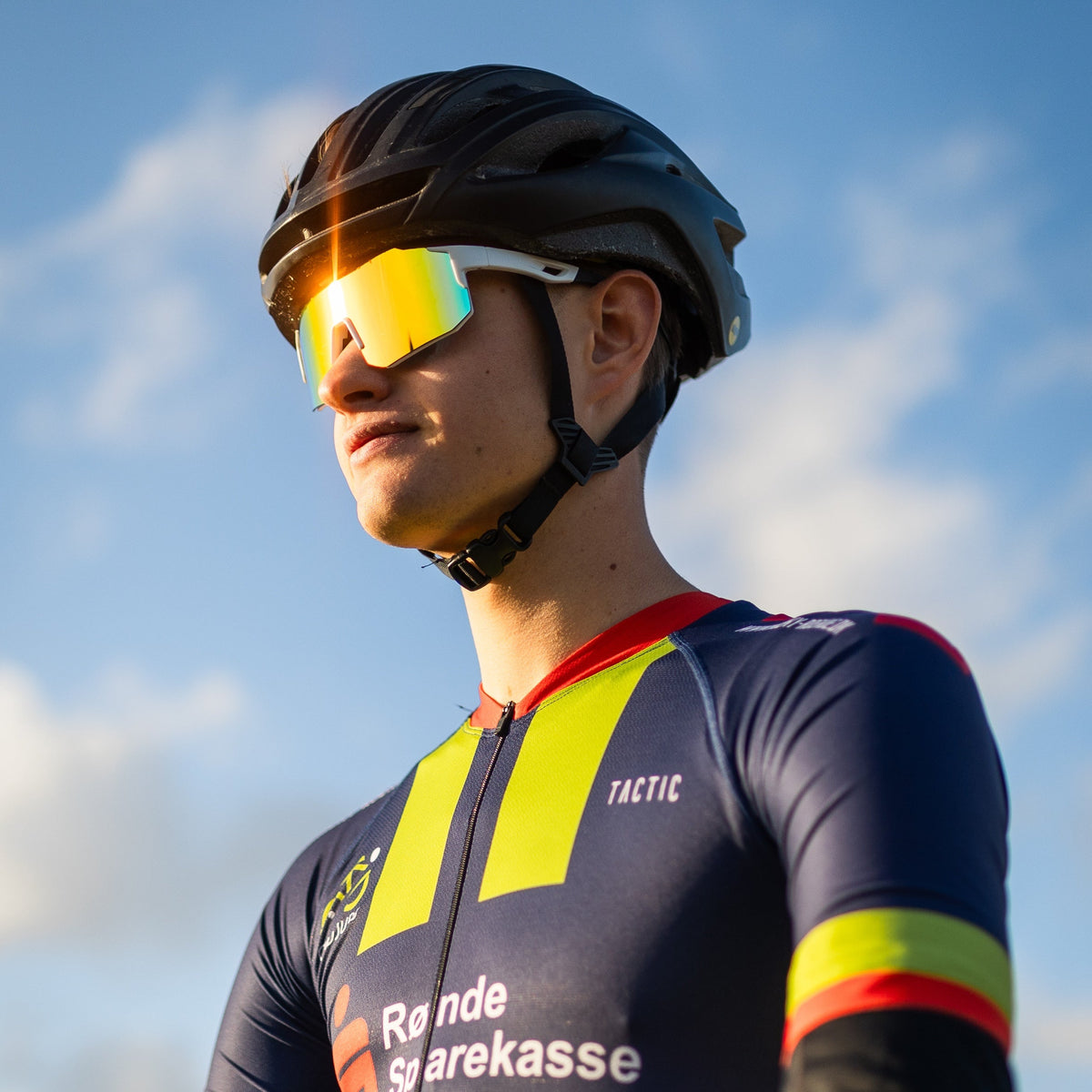 Cyklist med Noire Ruby sportsbriller i tropisk farve med gult spejlglas og sort cykelhjelm