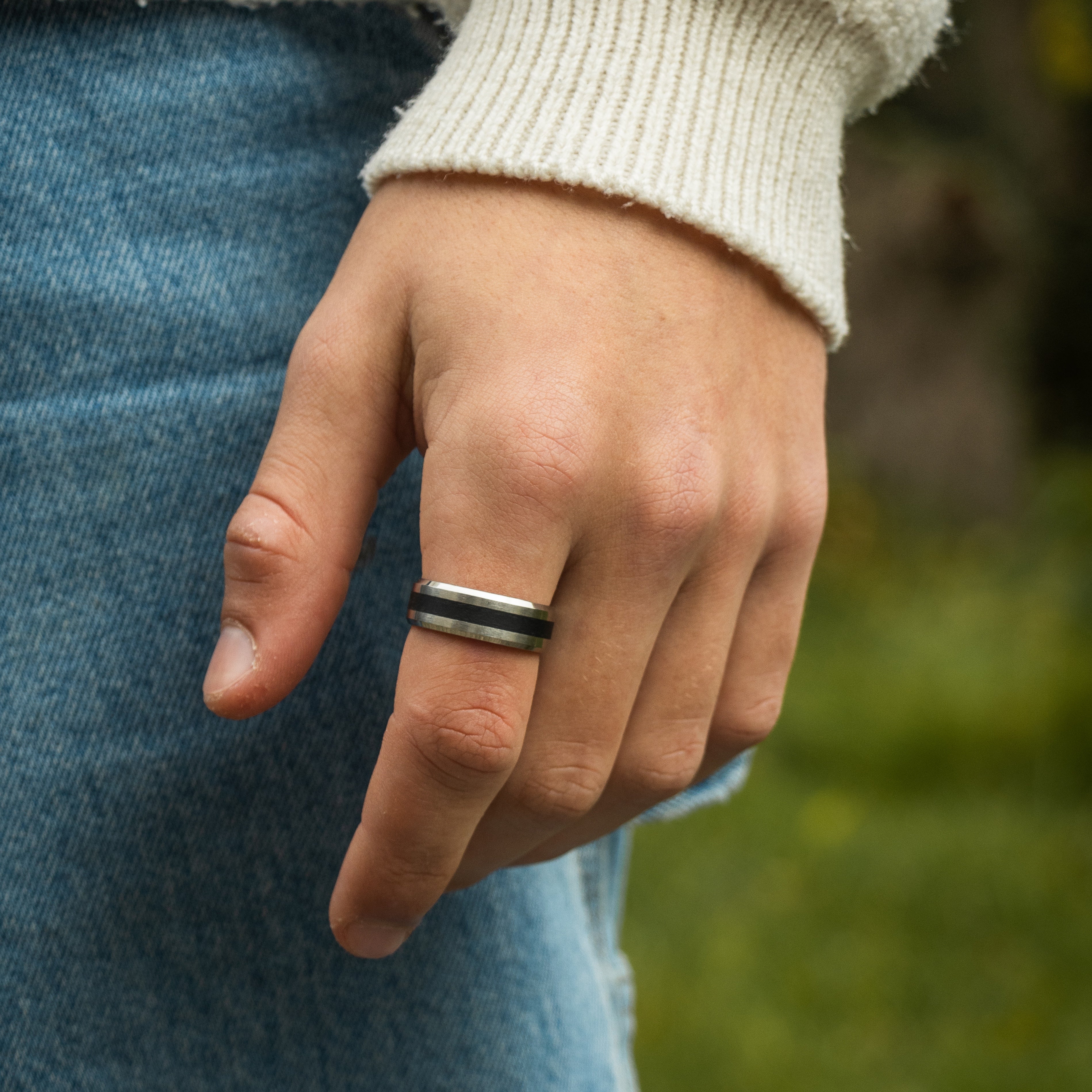 Sølvfarvet ring på finger med strik og denim baggrund