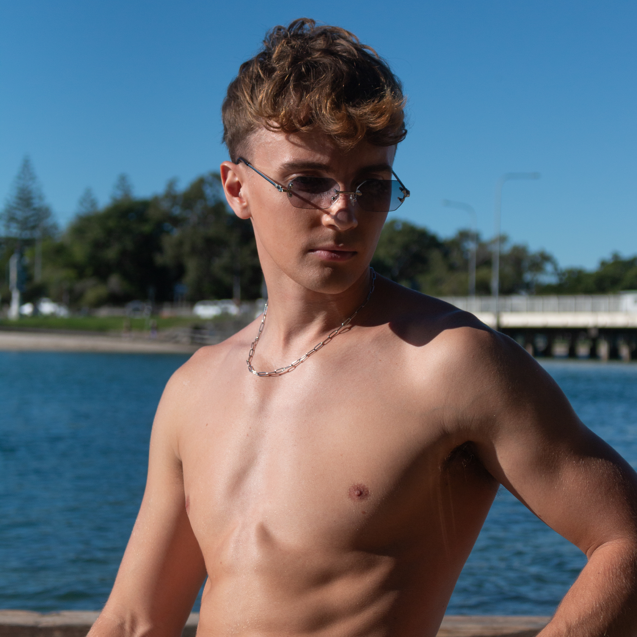 Young man with sunglasses and silver necklace at the beach