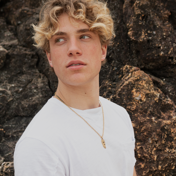 Ung mand bærer guldbelagt halskæde med ski mask vedhæng