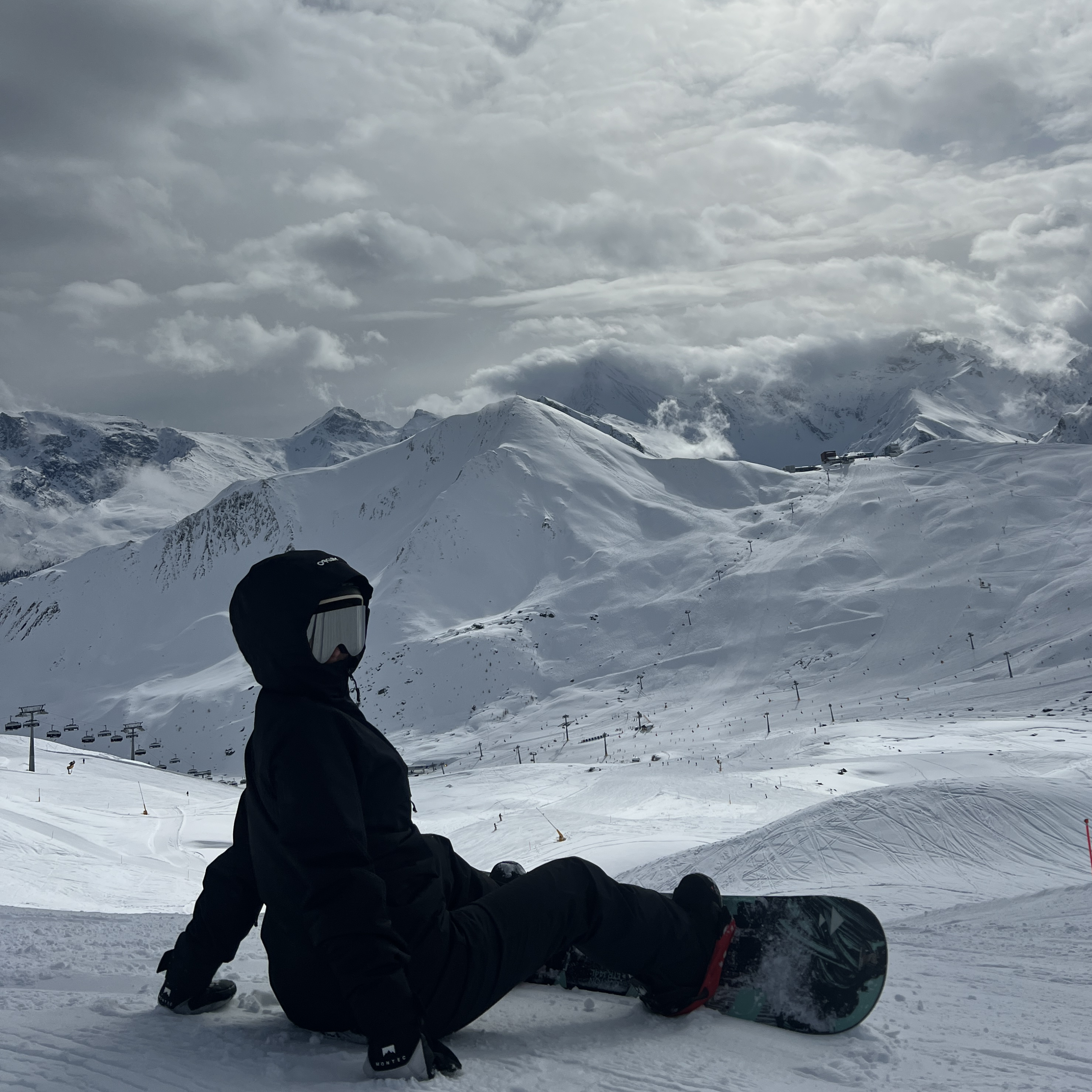 Snowboarder med Glaciér skibriller i grå nyder udsigt over snedækkede bjerge
