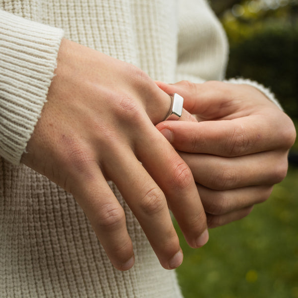 Sølvfarvet ring med hvid porcelænsdetalje på finger