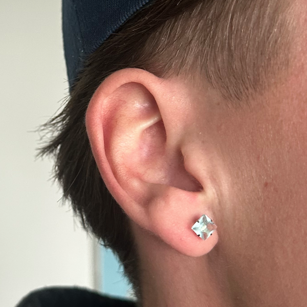 Sølv ørering med lyseblå krystalsten i øret på model