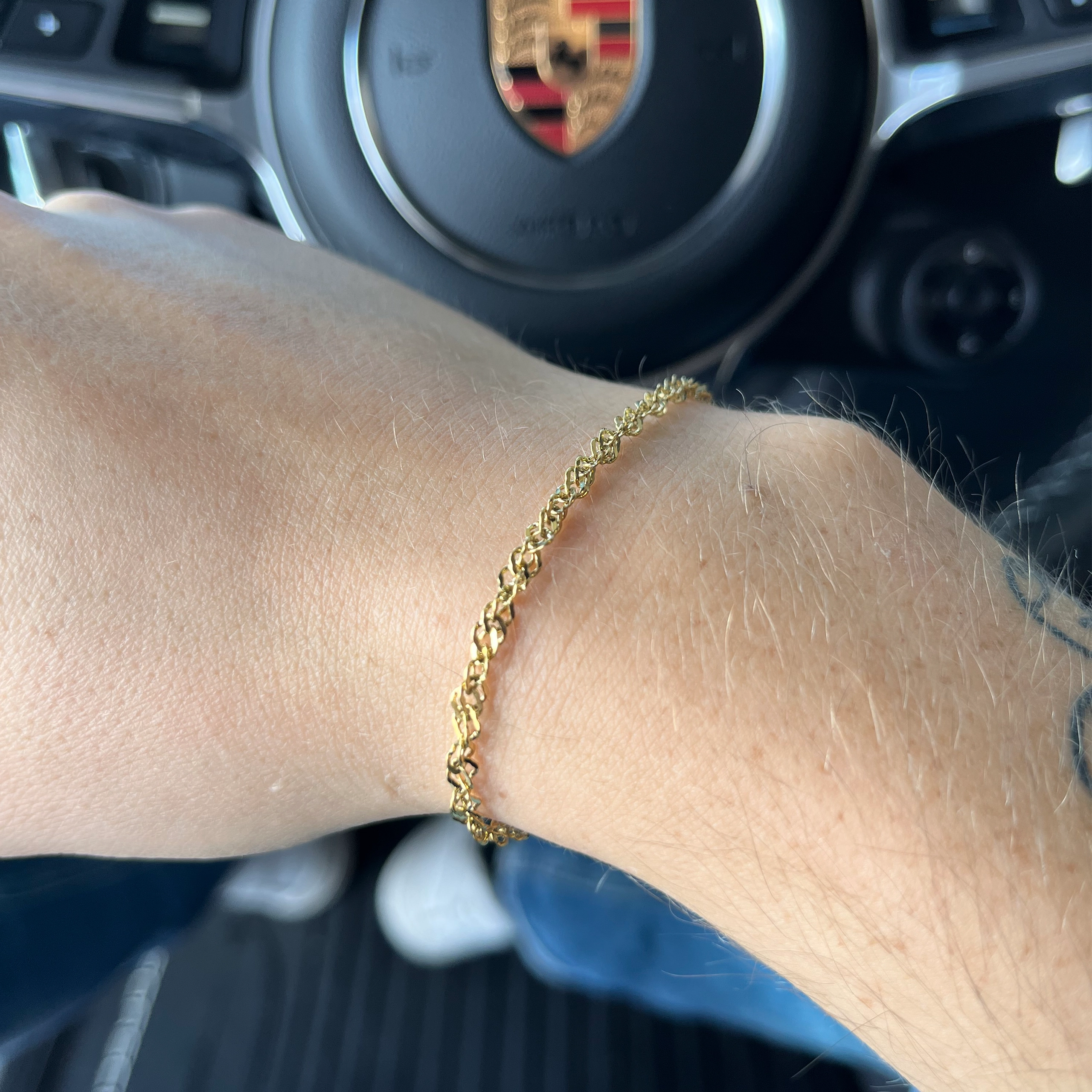 Guldbelagt armbånd på håndled i Porsche bil