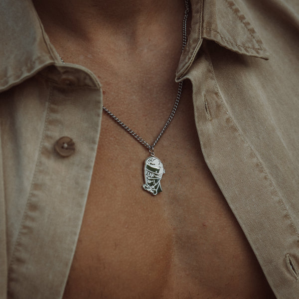 Sølvfarvet halskæde med Fear-vedhæng på beige skjorte