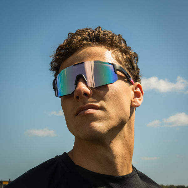Sportsbriller med spejlende flerfarvet glas på model under blå himmel