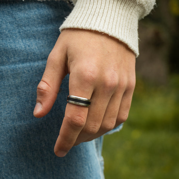 Sølvfarvet ring på finger med strik og denim baggrund