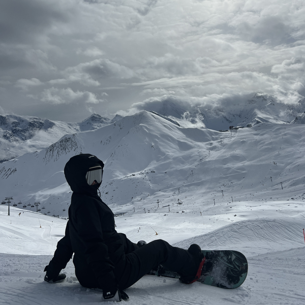 Snowboarder med Glaciér skibriller i grå nyder udsigt over snedækkede bjerge